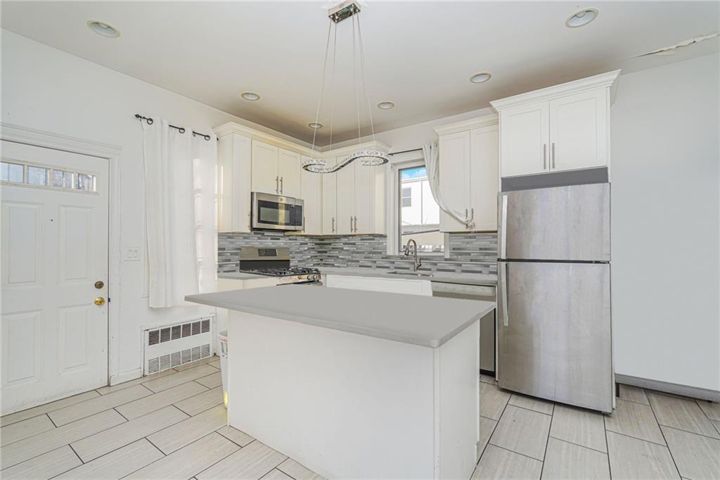 1764 East 24th Street Brooklyn, NY 11229 - Photo 9 of 16 a kitchen with kitchen island a white cabinets and refrigerator