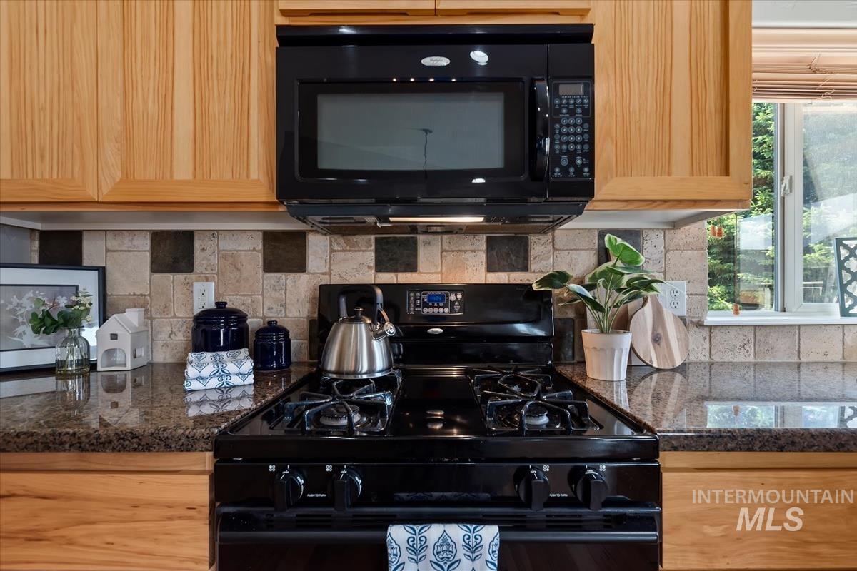 640 Southwest Miner Street Mountain Home, ID 83647 - Photo 33 of 35 Black range with an overhead microwave set against a mosaic tile backsplash