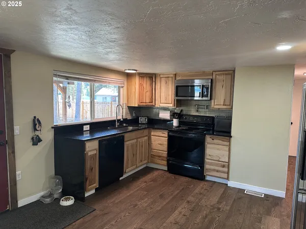 a kitchen with granite countertop a refrigerator and a stove top oven
