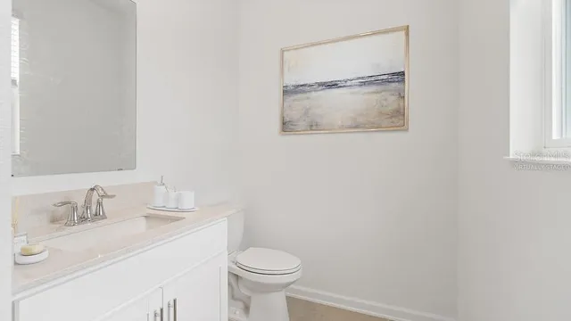 a bathroom with a granite countertop sink mirror vanity and toilet