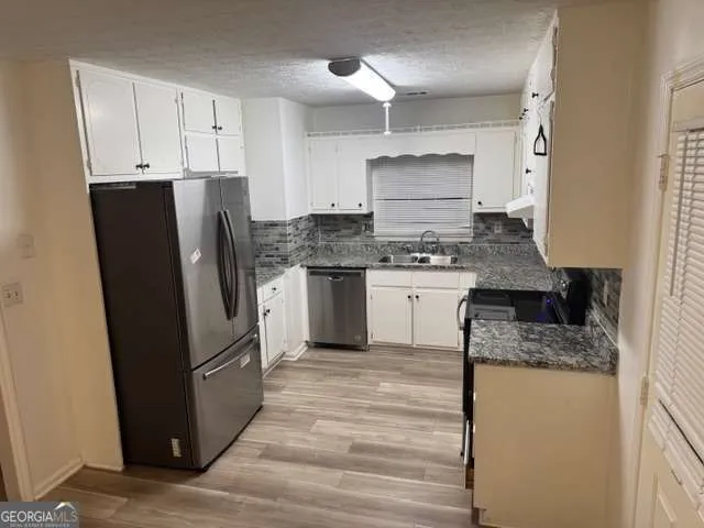 a kitchen with stainless steel appliances granite countertop a refrigerator stove and sink