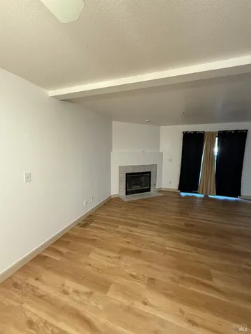 a view of empty room with wooden floor and fireplace