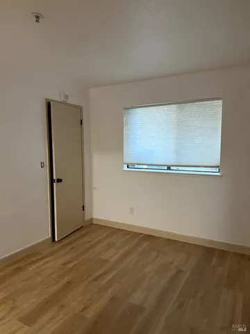a view of an empty room with wooden floor and closet