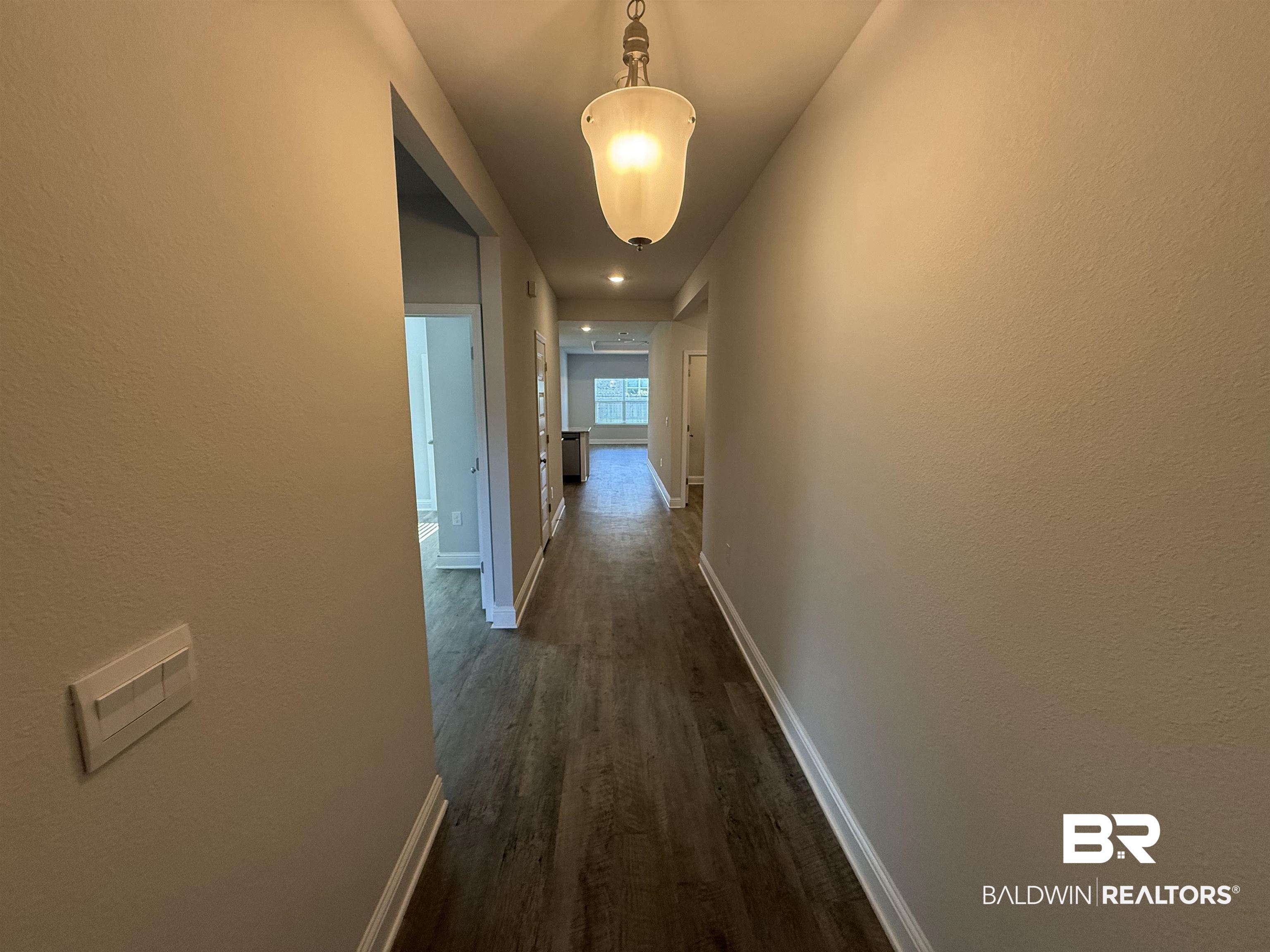 23247 Lieutenant Avenue Foley, AL 36535 - Photo 3 of 47 Hallway featuring wood-finish flooring, light neutral wall paint, and white baseboards