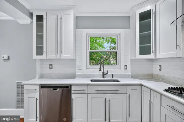 a kitchen with stainless steel appliances granite countertop white cabinets sink and window