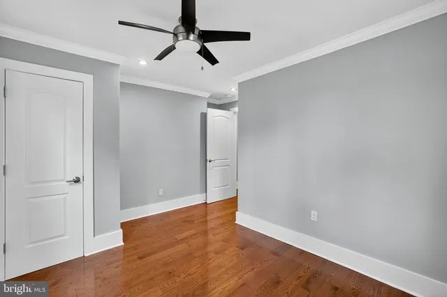an empty room with wooden floor closet and windows
