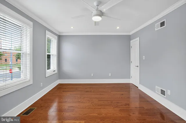 an empty room with wooden floor and windows