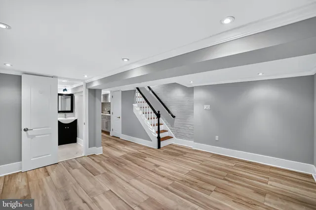 a view of an empty room with wooden floor kitchen view and a window