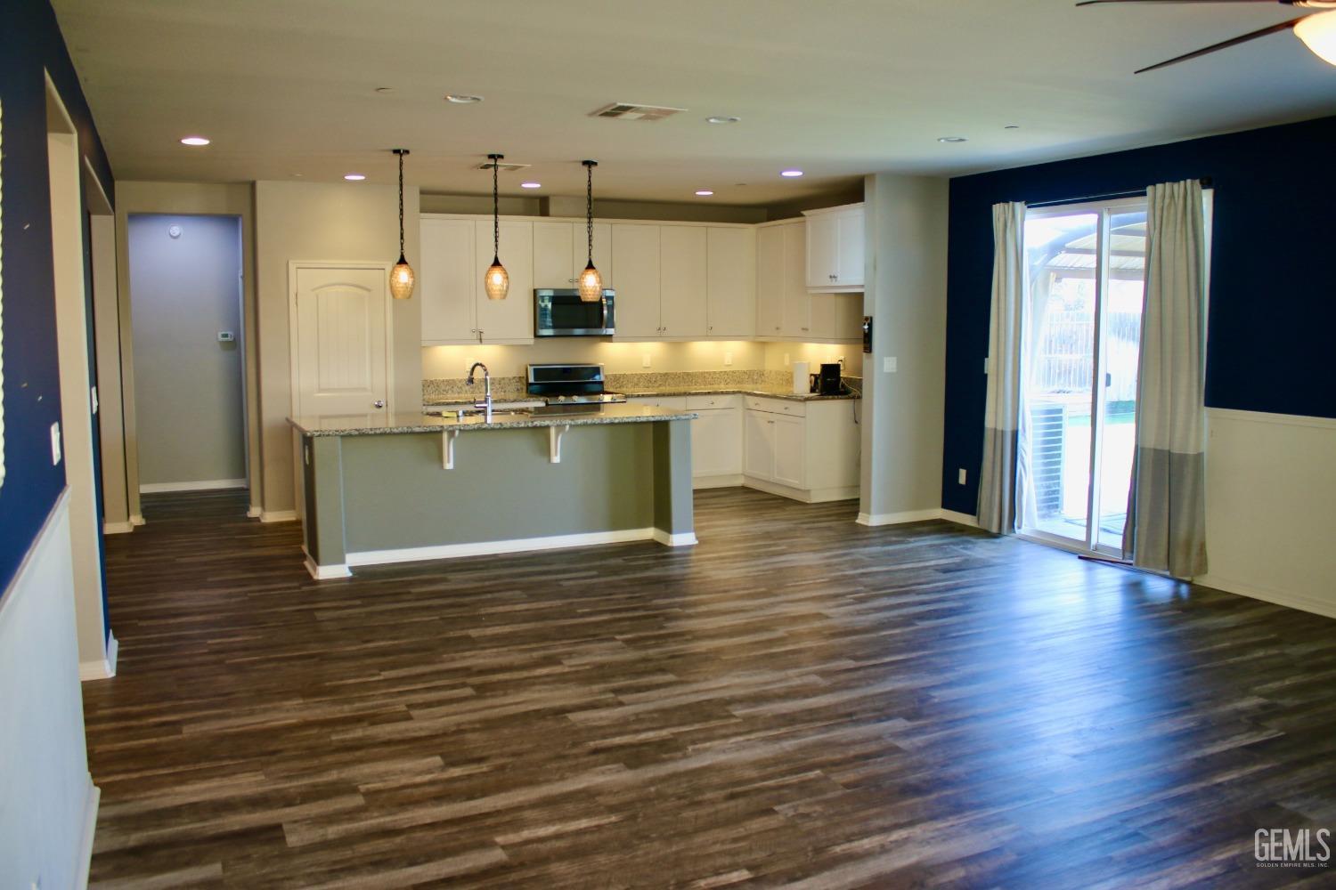 Undisclosed Address Bakersfield, CA 93313 - Photo 3 of 26 a open kitchen with kitchen island a sink dishwasher a refrigerator and a stove with wooden floor