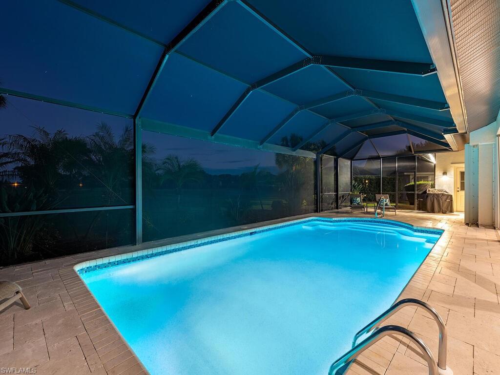 1832 Imperial Golf Course Boulevard Naples, FL 34110 - Photo 20 of 24 Pool at night with an outdoor pool, a sunroom, a lanai, and a patio