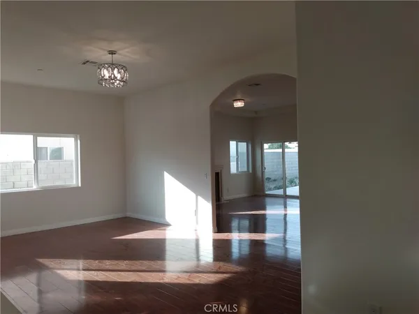 a hallway with wooden floor chandelier and windows