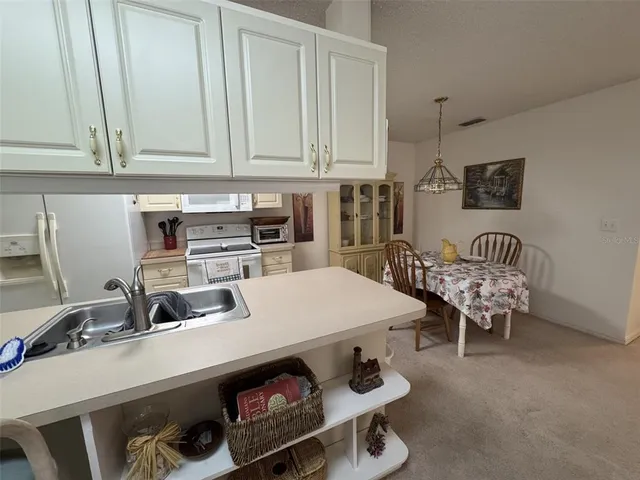a kitchen with a sink a stove and white cabinets
