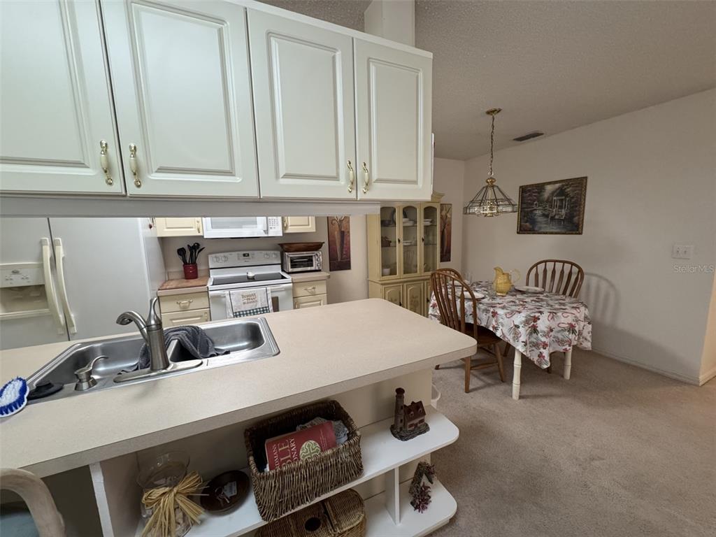 329 Genesis Pointe Drive, Unit 329 Lake Wales, FL 33859 - Photo 11 of 29 a kitchen with a sink a stove and white cabinets