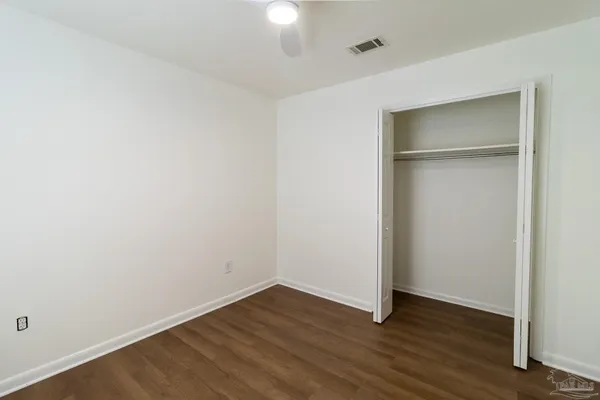 an empty room with wooden floor & closet area