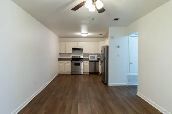 a kitchen with cabinets wooden floor and stainless steel appliances