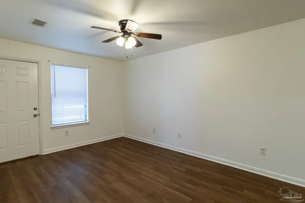 an empty room with wooden floor chandelier fan and windows