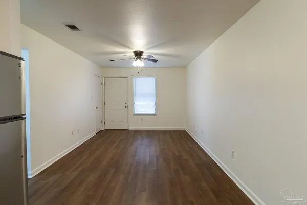 an empty room with wooden floor fan and windows