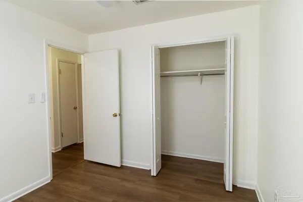 a view of an empty room with wooden floor & closet