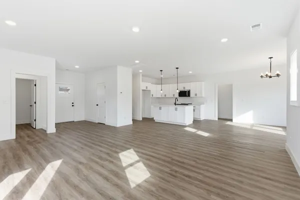 a view of kitchen and empty room with wooden floor