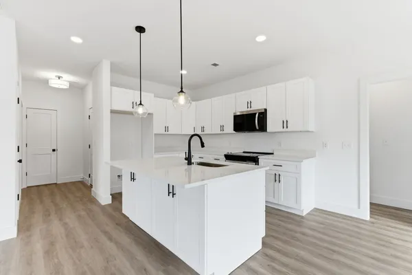 a kitchen with stainless steel appliances a stove top oven a sink a refrigerator and a window