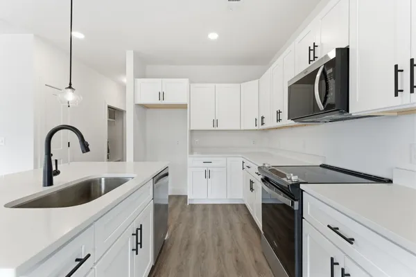 a kitchen with stainless steel appliances granite countertop a sink a stove and a wooden floors