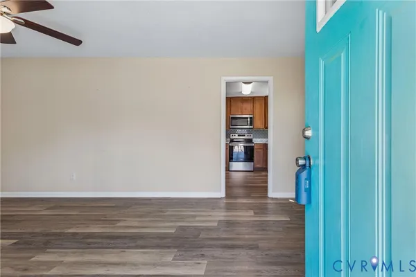 a view of empty room with wooden floor and fan