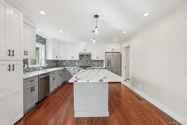 a kitchen with a sink a refrigerator and white cabinets