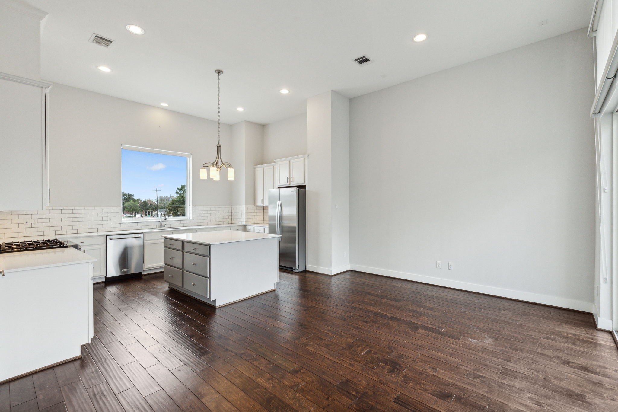 843 West 23rd Street, Unit B Houston, TX 77008 - Photo 14 of 34 a large white kitchen with a refrigerator a stove top oven a sink dishwasher and white cabinets with wooden floor