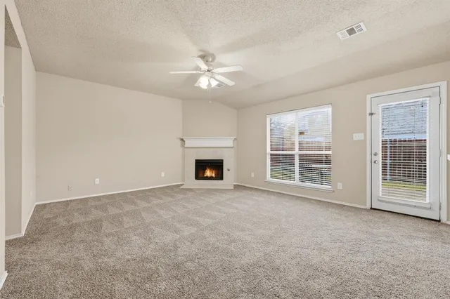 an empty room with windows and ceiling fan