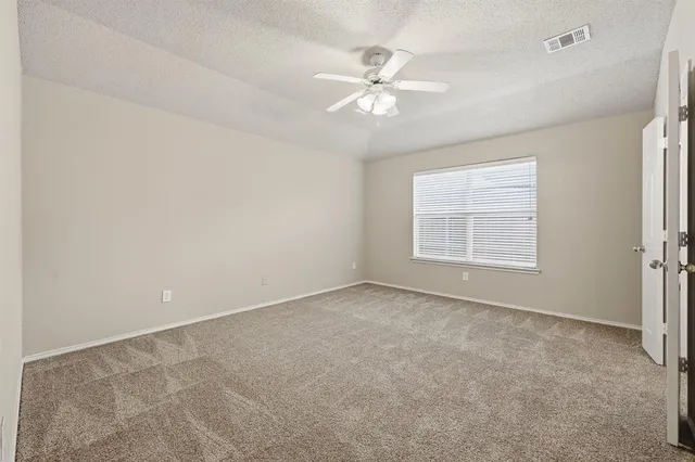 an empty room with windows and chandelier fan