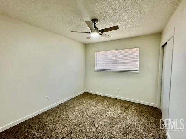 an empty room with a window and a ceiling fan