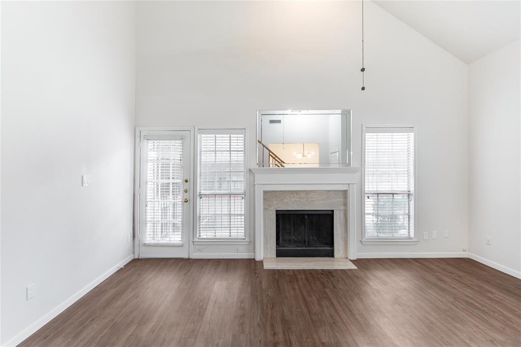 12680 Hillcrest Road, Unit 4101 Dallas, TX 75230 - Photo 5 of 37 Spacious living area featuring a vaulted ceiling, wood-finish flooring, and a fireplace with a stone surround and mantle