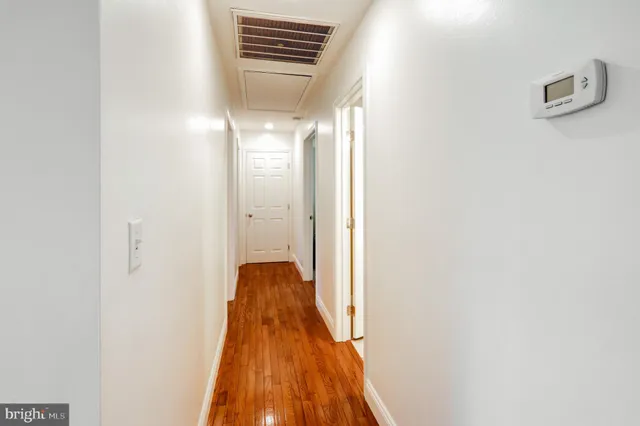 a view of a hallway with wooden floor and a bathroom