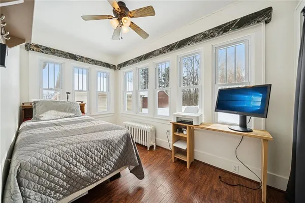 a bedroom with a bed a desk and chair with wooden floor