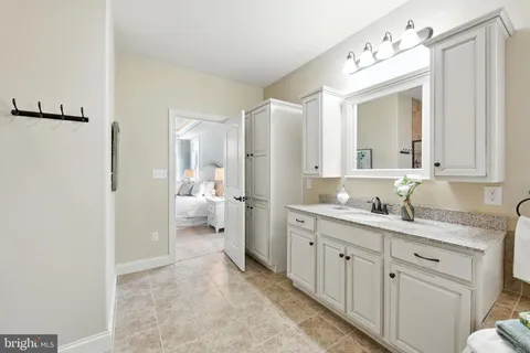a en suite bathroom with a granite countertop sink and a mirror