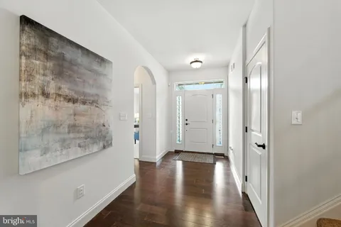 a view of a hallway with wooden floor and a bathroom
