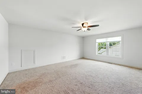 an empty room with a window and a ceiling fan