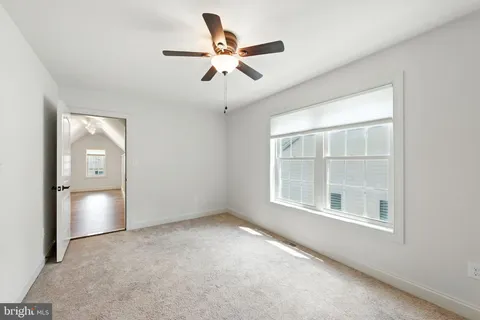 an empty room with ceiling fan and windows