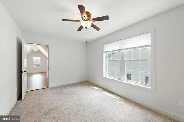 an empty room with ceiling fan and windows