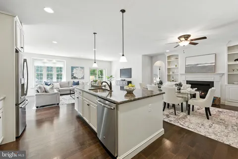 a kitchen with stainless steel appliances granite countertop a stove and a view of living room