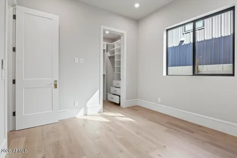 a view of an empty room with wooden floor and a ceiling fan