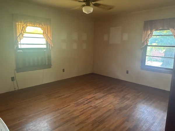an empty room with wooden floor and windows