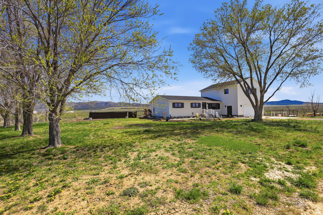 830 North Stone Road Snowville, UT 84336 - Photo 59 of 69 Back of property with a mountain view, a lawn, and a patio area