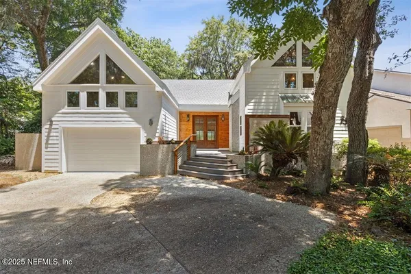 a view of a house with a yard and large tree