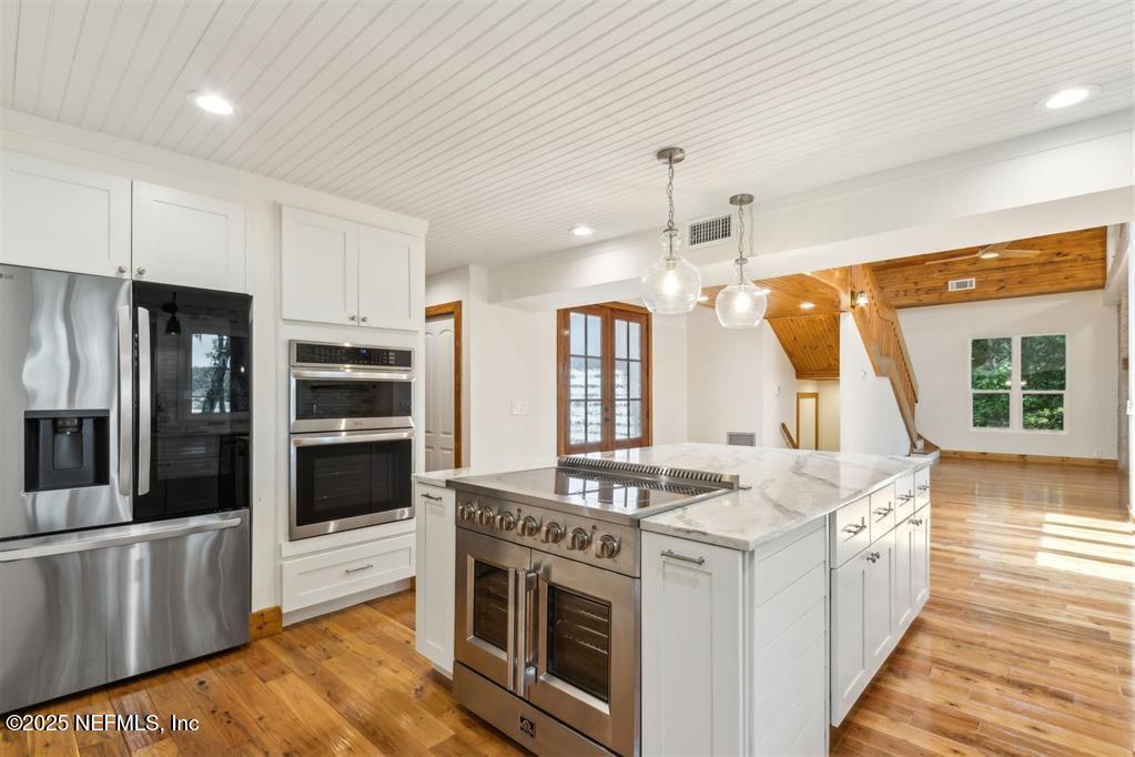 22 Belted Kingfisher Road Fernandina Beach, FL 32034 - Photo 14 of 70 a kitchen with stainless steel appliances kitchen island granite countertop a stove a sink and a refrigerator