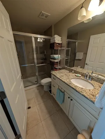 a bathroom with a granite countertop sink a toilet and shower