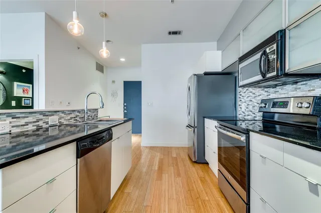 a kitchen with kitchen island a counter space a sink appliances and cabinets