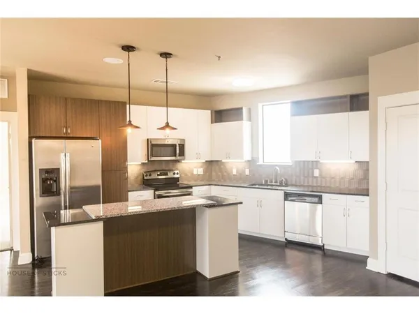 a kitchen with stainless steel appliances a sink a stove a refrigerator and cabinets