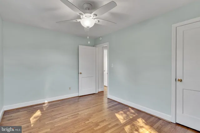 an empty room with wooden floor and ceiling fan