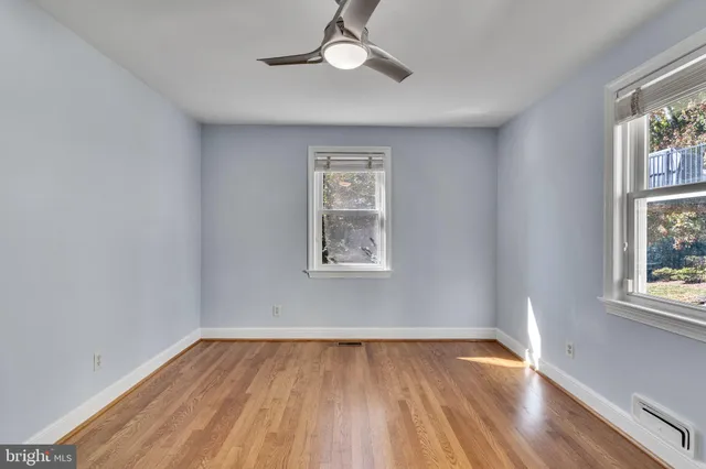 a view of empty room with wooden floor and fan